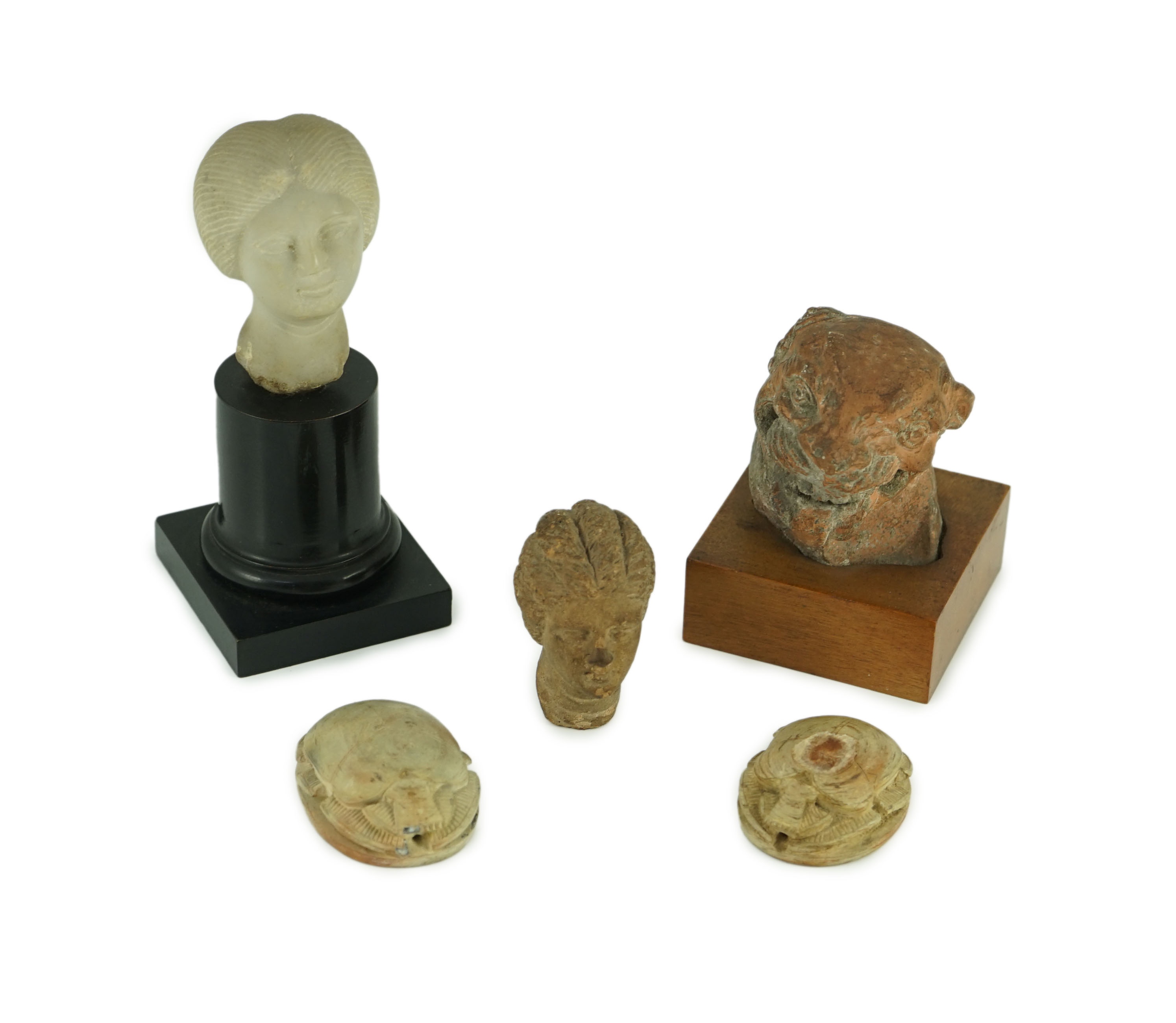 A group of antiquities comprising two commemorative scarabs, an Egyptian style gypsum head, and two antique terracotta heads